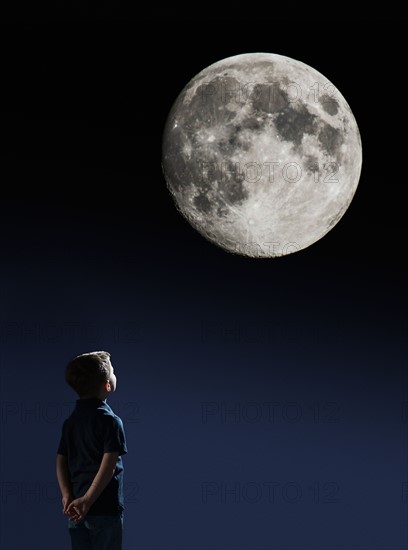 Boy (4-5) looking at full moon.