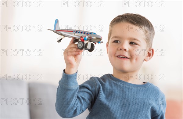 Boy (4-5) playing with toy plane.