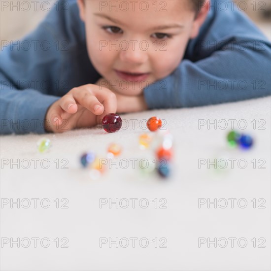 Boy (4-5) playing with marbles.