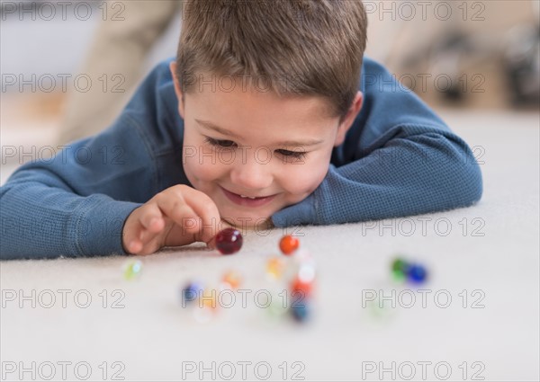 Boy (4-5) playing with marbles.