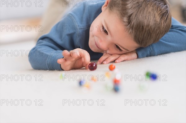 Boy (4-5) playing with marbles.