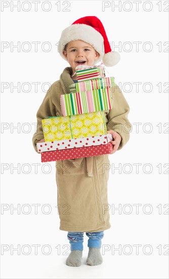 Portrait of boy (4-5) carrying christmas presents.