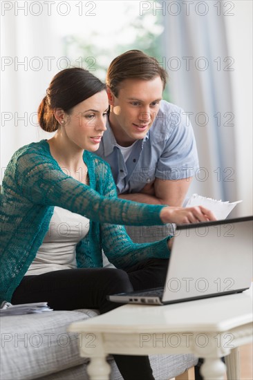 Couple using laptop together to pay bills.