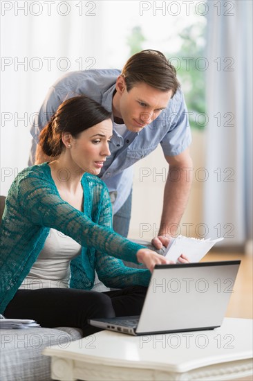 Couple using laptop together to pay bills.