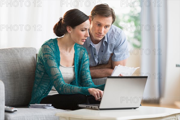 Couple using laptop together to pay bills.