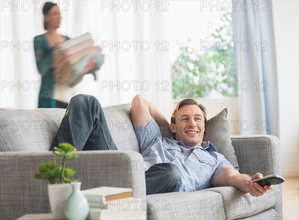 Man lying on sofa watching tv.