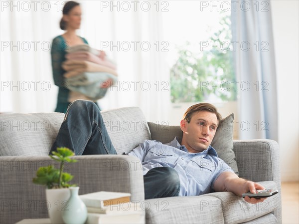 Man lying on sofa watching tv.