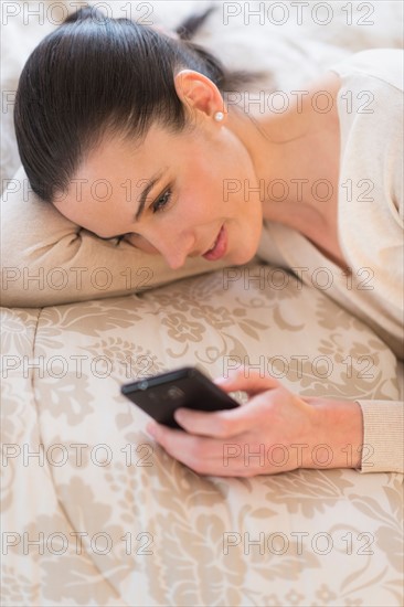 Woman lying on bed and using phone.