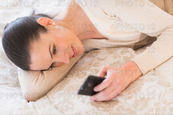 Woman lying on bed and using phone.