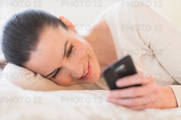 Woman lying on bed and using phone.