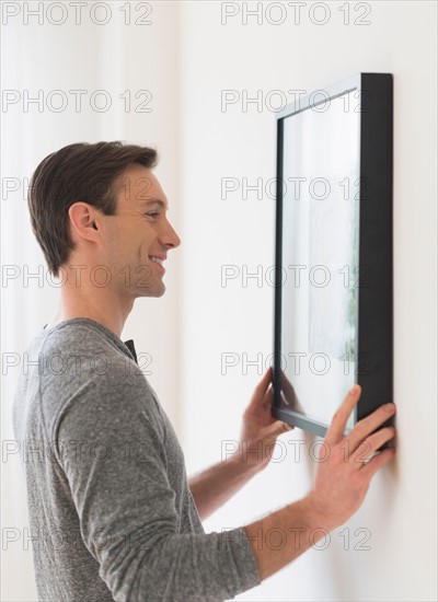 Man hanging picture on wall.