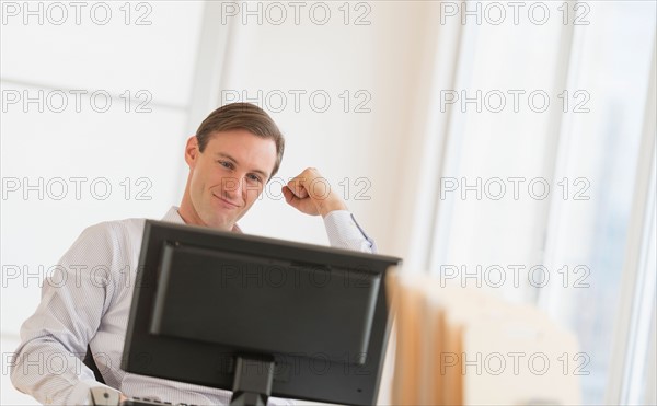 Office worker cheering in front of computer.