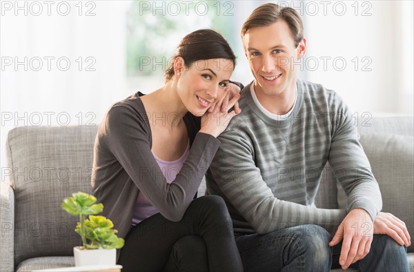 Portrait of couple sitting on sofa.