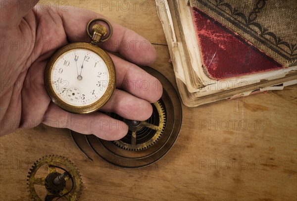 Hands holding antique clock and gears.