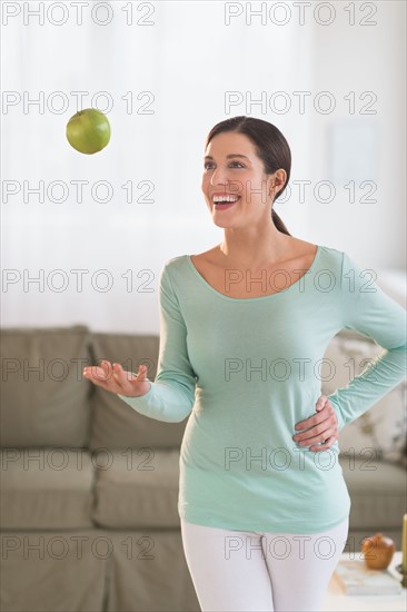 Woman juggling with apple at home.