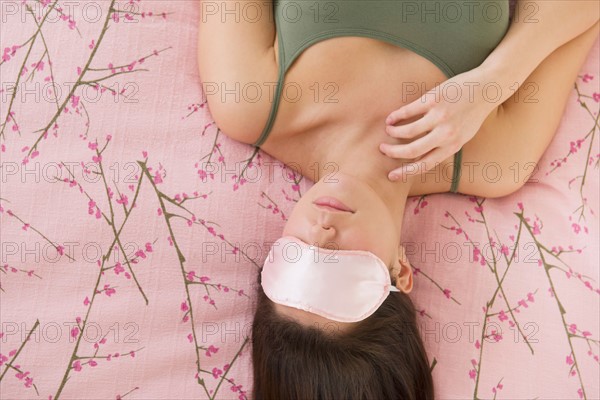 Woman with sleep mask lying on bed .