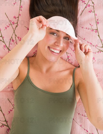 Woman with sleep mask lying on bed .