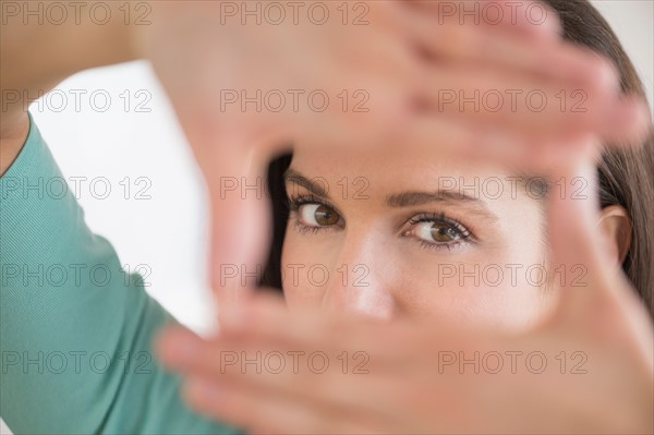 Woman looking at camera through handsframe.