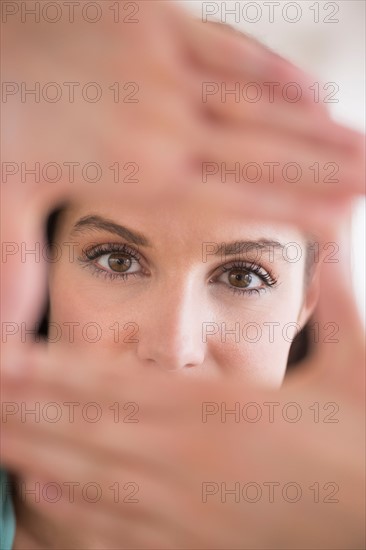 Woman looking at camera through handsframe.