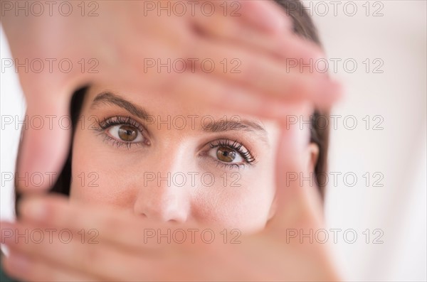 Woman looking at camera through handsframe.
