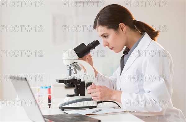 Scientist looking through microscope.