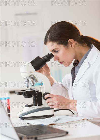 Scientist looking through microscope.