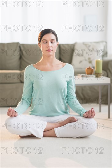 Woman meditating in living room.