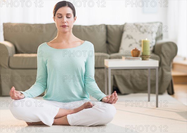 Woman meditating in living room.