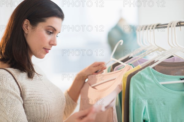 Woman looking at blouses at store.