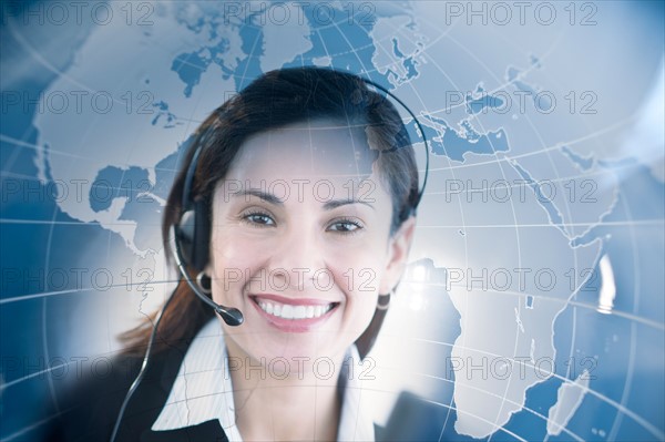 Woman with headset with world map in background.