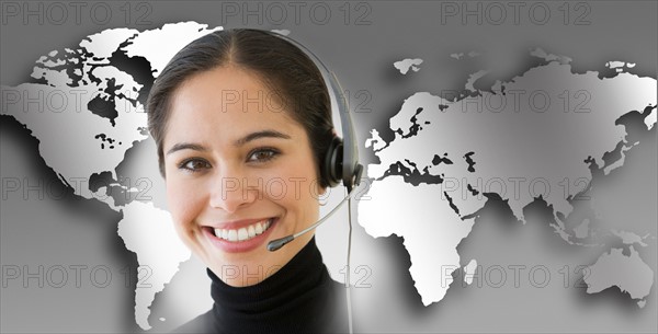 Woman with headset with world map in background.
