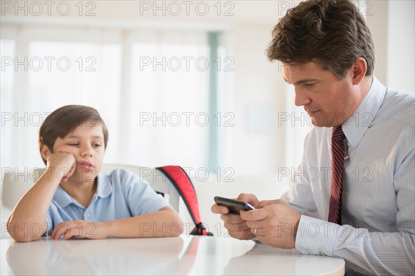 Father and son (8-9) sitting at table