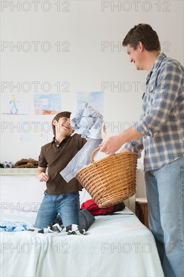 Father and son (8-9) collecting dirty clothes