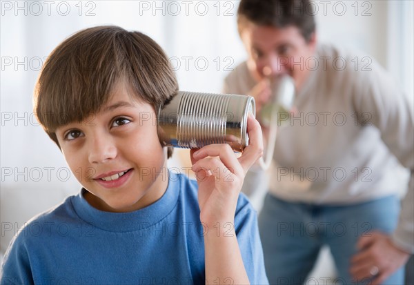 Father and son (8-9) playing with tin can phone