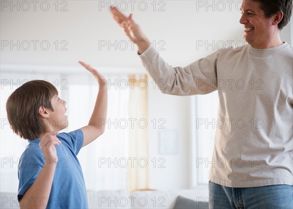 Father and son (8-9) giving each other high five