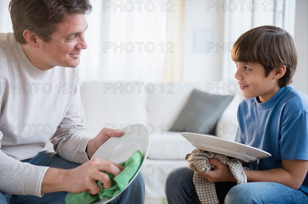 Father and son (8-9) drying dishes