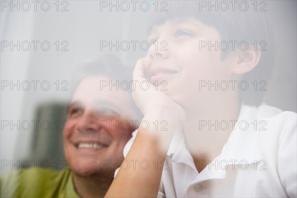 Son (8-9) and father looking through window