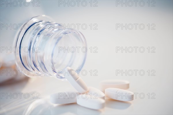 Studio Shot of white pills spilling out of bottle