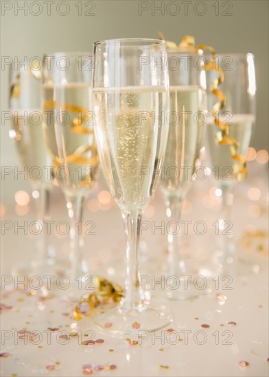 Champagne flutes on table decorated with confetti and streamer