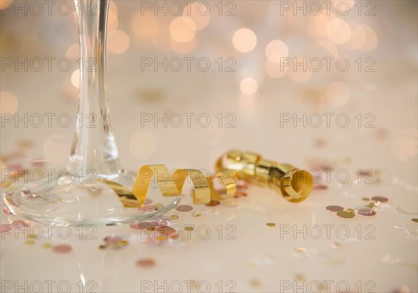 Champagne flute on table decorated with confetti and streamer