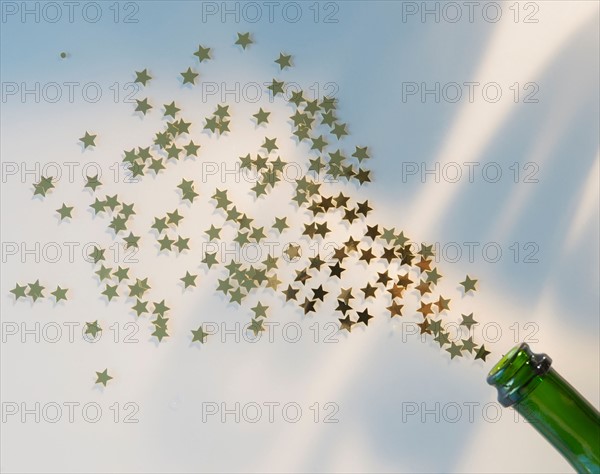 Star shape confetti splashing out of champagne bottle