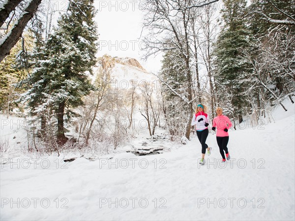 Two women jogging in winter forest