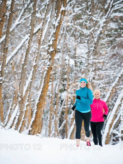 Two women jogging in winter forest