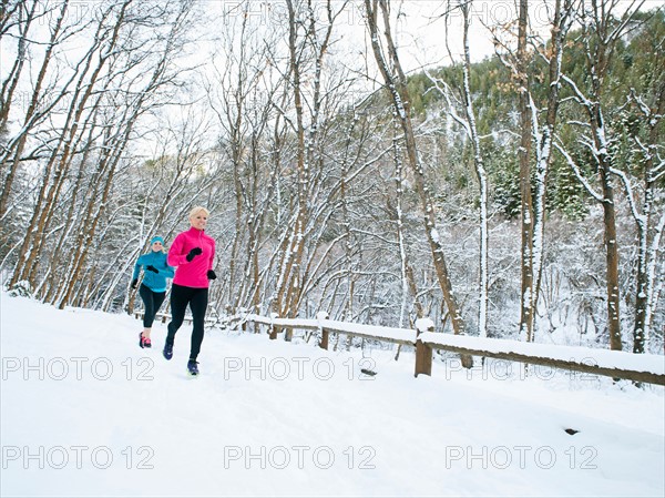 Two women jogging in winter forest