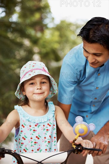 Man assisting girl (6-7) riding bicycle