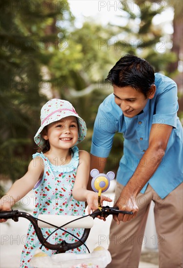 Man assisting girl (6-7) riding bicycle