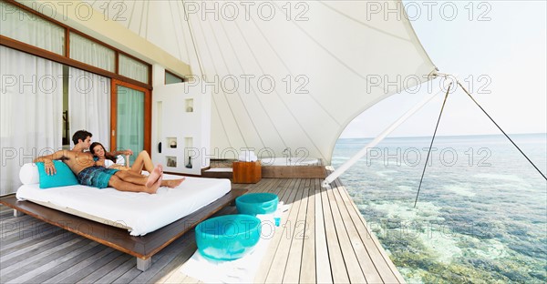 Couple relaxing on deck by sea