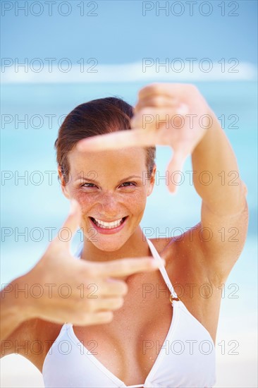 Portrait of woman looking through finger frame