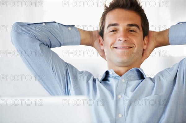 Portrait of man relaxing, hands behind head