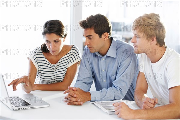 Coworkers at table looking at laptop